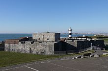 A gray, squat stone castle by the sea shore