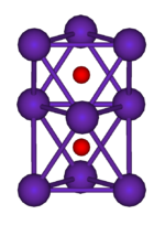 The ball-and-stick diagram shows two regular octahedra which are connected to each other by one face. All nine vertices of the structure are purple spheres representing rubidium, and at the centre of each octahedron is a small red sphere representing oxygen.