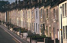 Yellow stone terraced houses alongside a steep road.