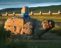 Photograph of a field with a large stone tortoise