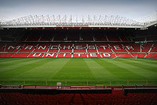 A stand of a football stadium. The seats are red, and the words 