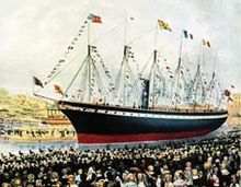 A crowd of people watch a large black and red ship with one funnel and six masts adorned with flags