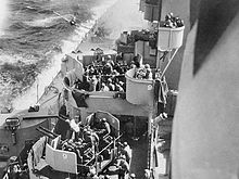 Diving airplane about to hit the side of a warship.