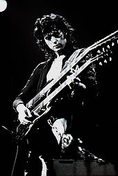 A black and white photograph of Jimmy Page playing a double-necked guitar