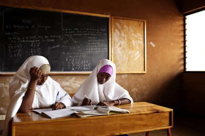 Girls studying hard, blackboard behind