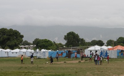 Children play football in front of the temporary shelters, Santo